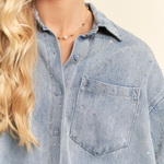 Close-up of a person wearing a light blue denim shirt with a neutral background