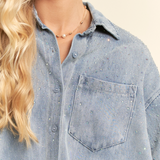 Close-up of a person wearing a light blue denim shirt with a neutral background