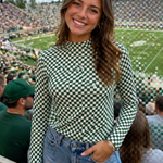 Woman in a checkered top and denim shorts at a sports event