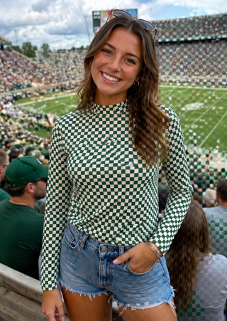 Woman in a checkered top and denim shorts at a sports event