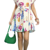 Woman wearing a floral dress holding a green handbag on a white background