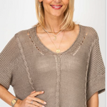 Woman wearing a brown knit top with a plain background