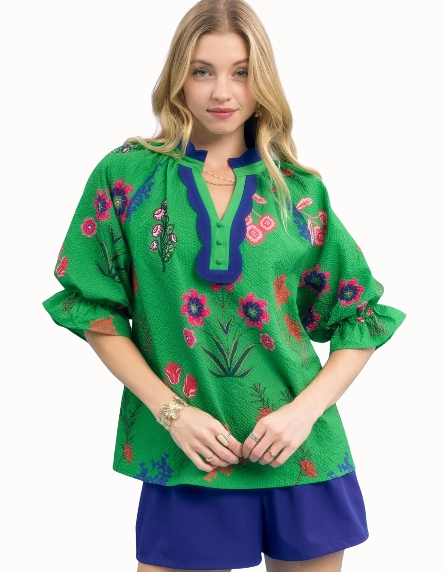 Woman wearing a green embroidered blouse with floral patterns on a white background