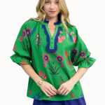 Woman wearing a green embroidered blouse with floral patterns on a white background