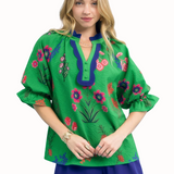 Woman wearing a green embroidered blouse with floral patterns on a white background
