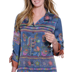 Woman wearing a colorful embroidered shirt with rolled-up sleeves on a white background