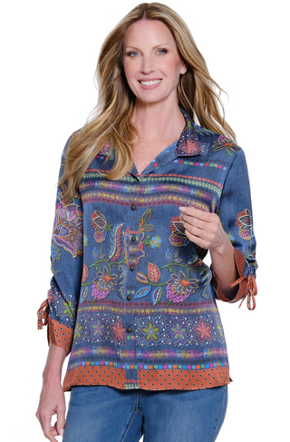 Woman wearing a colorful embroidered shirt with rolled-up sleeves on a white background