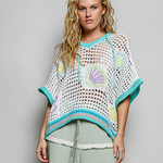 Woman wearing a crochet poncho with shell patterns on a plain background