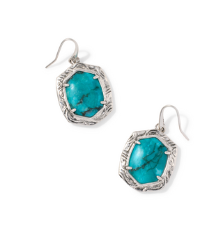 A pair of silver dangle earrings featuring irregular turquoise-colored stone inlays, displayed on a clean white background.
