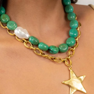 Necklace with green beads and a gold chain featuring a star pendant on a person.