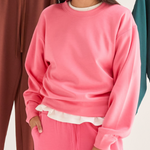 Person wearing a pink fleece outfit with a white shirt underneath, standing against a neutral background.