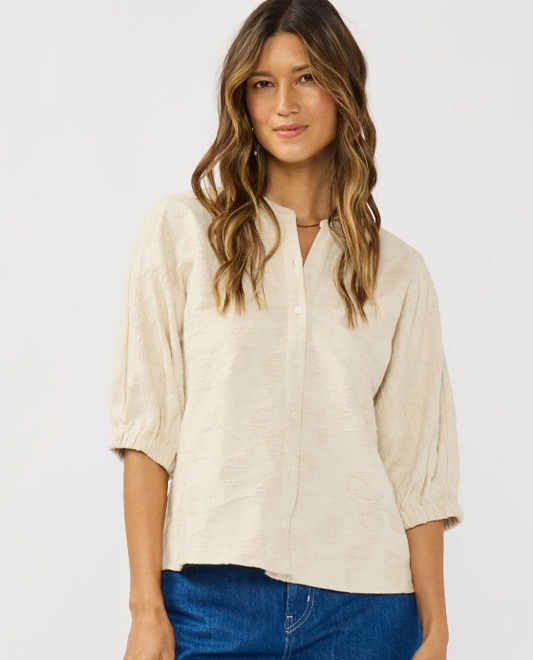 Woman wearing a beige blouse and blue jeans on a white background