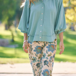 Woman wearing a light blue shirt and floral pants in a park setting