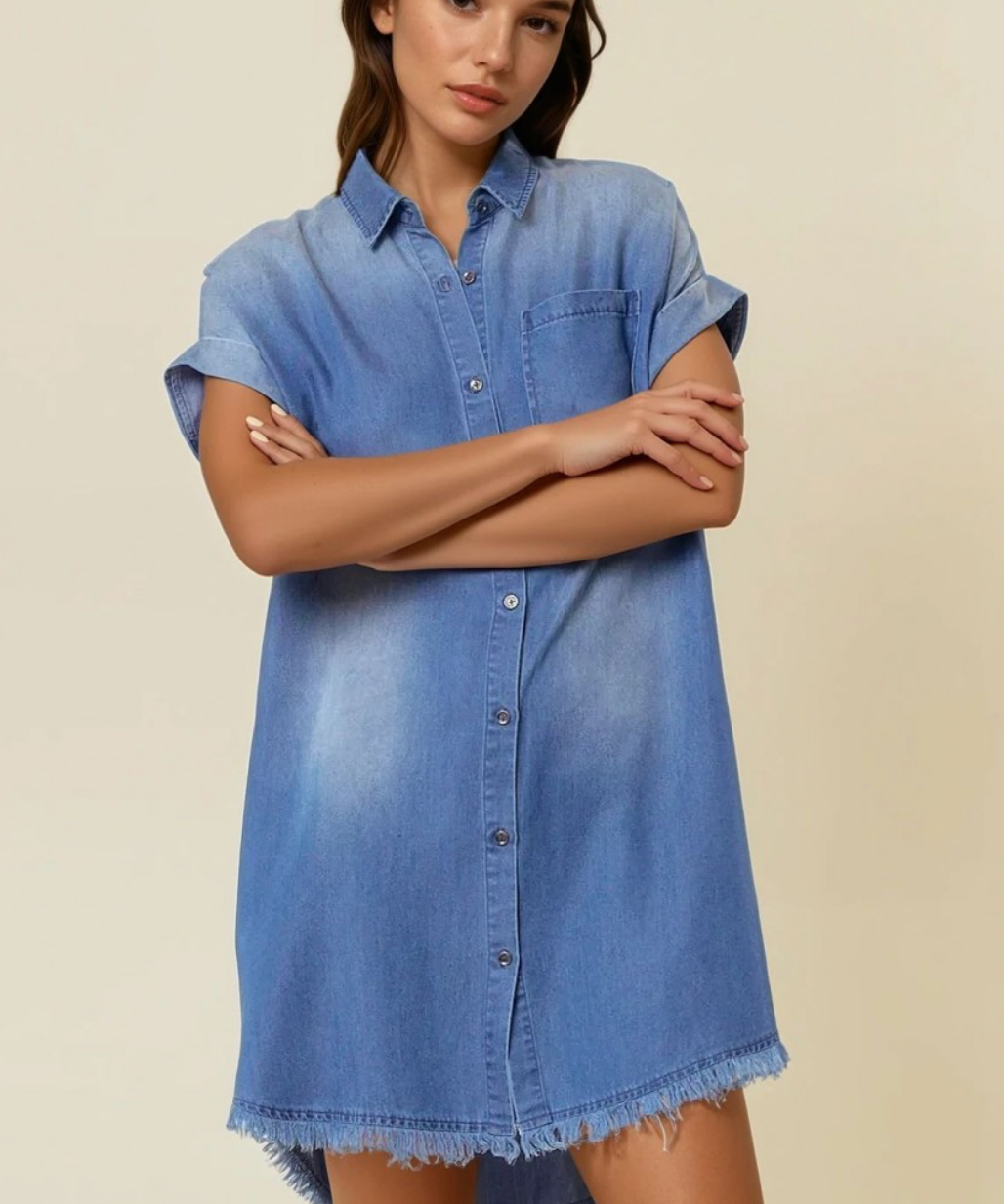 Woman wearing a blue denim dress against a beige background