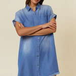 Woman wearing a blue denim dress against a beige background