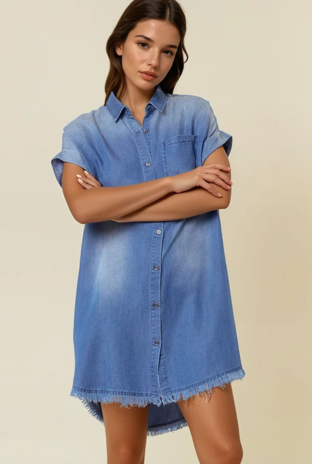Woman wearing a blue denim dress against a beige background