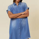 Woman wearing a blue denim dress against a beige background
