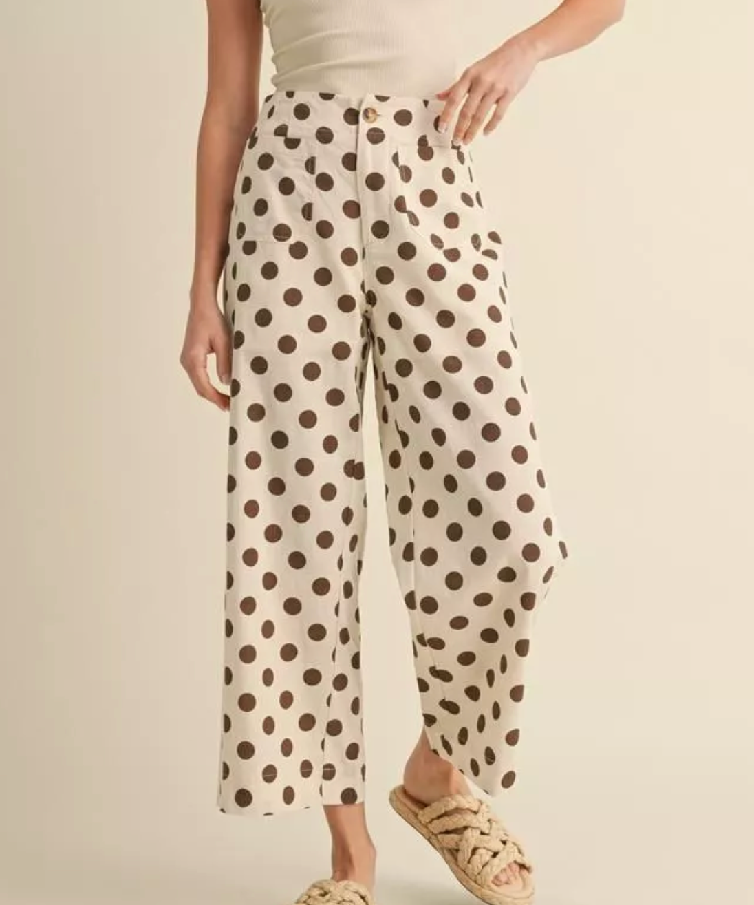 Person wearing polka dot pants on a beige background
