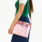 Person wearing a green top and blue pants with a pink crossbody bag on a white background