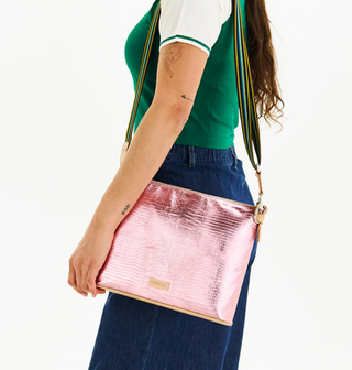 Person wearing a green top and blue pants with a pink crossbody bag on a white background