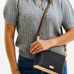 Person wearing a gray cable knit sweater holding a black handbag with a strap.