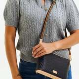 Person wearing a gray cable knit sweater holding a black handbag with a strap.