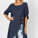 Woman wearing a navy blue long top with floral pants on a white background