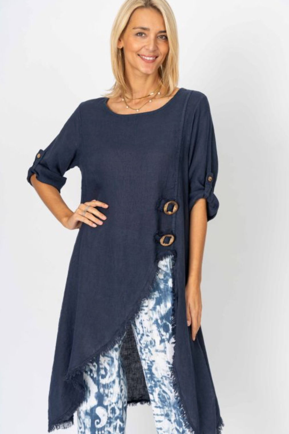 Woman wearing a navy blue long top with floral pants on a white background