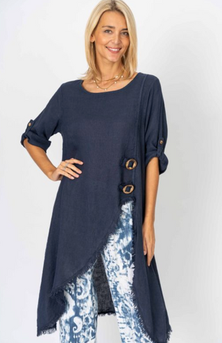 Woman wearing a navy blue long top with floral pants on a white background