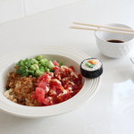 Sashimi platter with sushi roll, wasabi, and soy sauce on a white surface
