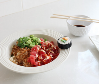 Sashimi platter with sushi roll, wasabi, and soy sauce on a white surface