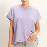 Woman wearing a light purple oversized t-shirt and denim shorts on a plain background