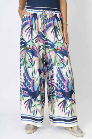 Colorful tropical print pants worn by a person on a white background
