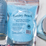 Package of 'Sunday Beach' Dead Sea Salt blend with a bottle and other products in the background.