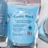 Package of 'Sunday Beach' Dead Sea Salt blend with a bottle and other products in the background.