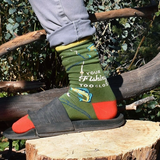 Person wearing colorful socks with fishing-themed design on a wooden log outdoors.
