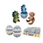 Dinosaur surprise eggs and plush dinosaur toys on a plain white background. The set includes two gray cracked-egg surprise eggs with paper bands, a box of multiple eggs, and three plush dinosaur figures emerging from or displayed with the eggs: a green dinosaur, a blue dinosaur on a pedestal, and a brown dinosaur with red teeth.