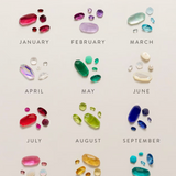 A decorative monthly gemstone chart titled 'FIND YOURS' with twelve colored gemstone clusters arranged in a grid, labeled January through December on a light beige background.