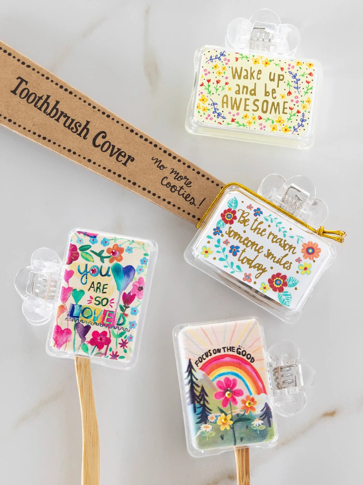 Set of colorful toothbrush covers with motivational phrases on a marble surface.