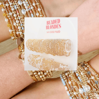 Gold beaded hair ties with 'Beaded Blondes' packaging on a blurred background