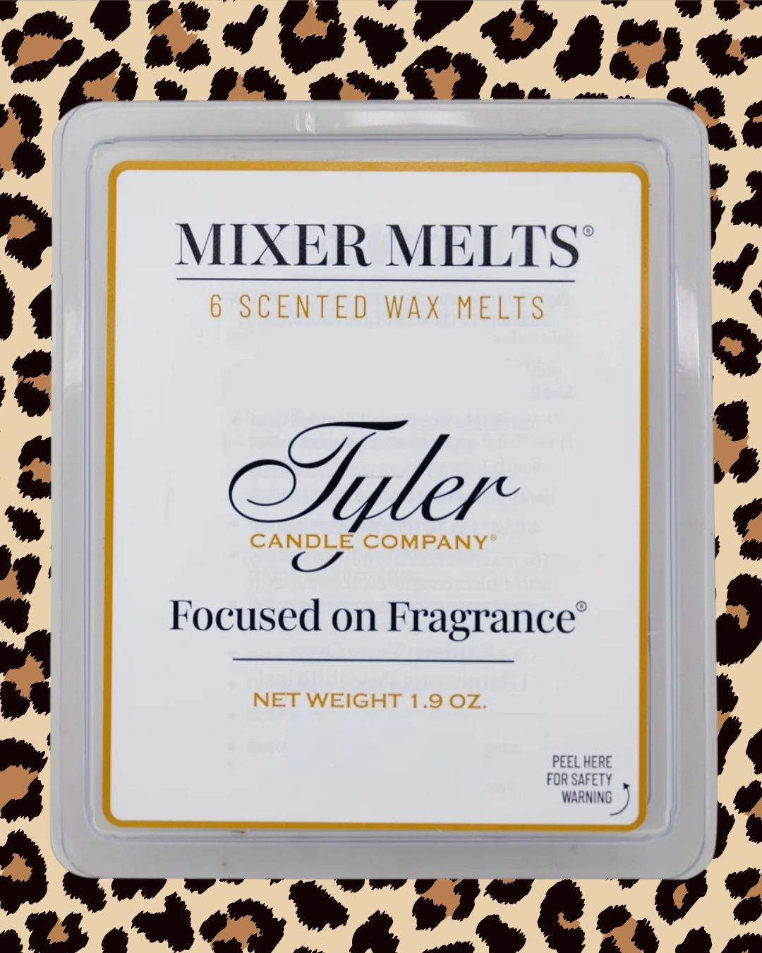 A square plastic clamshell package of Tyler Candle Company 'Focused on Fragrance' scented wax melts. The white label features black and gold typography, set against a leopard print background.