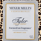 A square plastic clamshell package of Tyler Candle Company 'Focused on Fragrance' scented wax melts. The white label features black and gold typography, set against a leopard print background.