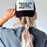 Person wearing a cap with 'Trailer Park Pretty' text on a plain background