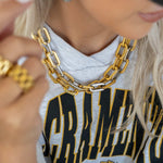 Person wearing a gold chain necklace with a blurred background