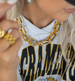 Person wearing a gold chain necklace with a blurred background