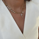 Gold necklace with pearls and a cross pendant on a white background