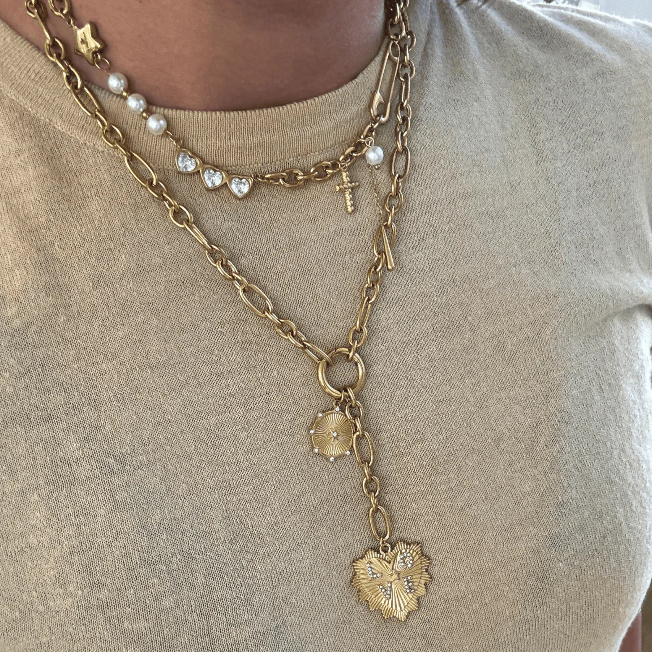 Gold chain necklace with heart pendant on a beige background