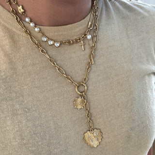 Gold chain necklace with heart pendant on a beige background