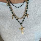 Green beaded necklace with gold cross pendant on a white top