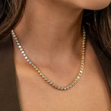 Close-up of a person wearing a delicate gold necklace with small stones.